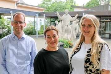 Br. Nils Flitter, Julia Dahmen und Lena Freitag vor einer steinernen Don Bosco Statue.