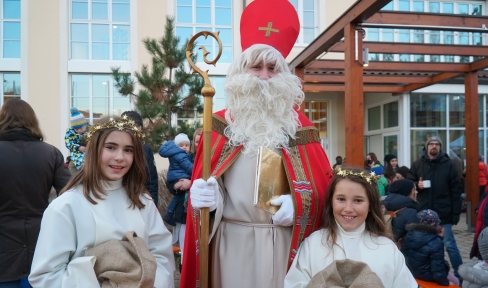 Der Nikolaus und 2 Mädchen als Engel verkleidet lächeln in die Kamera.