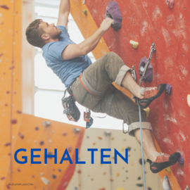 Gehalten. Ein Mann klettert eine Wand hinauf.